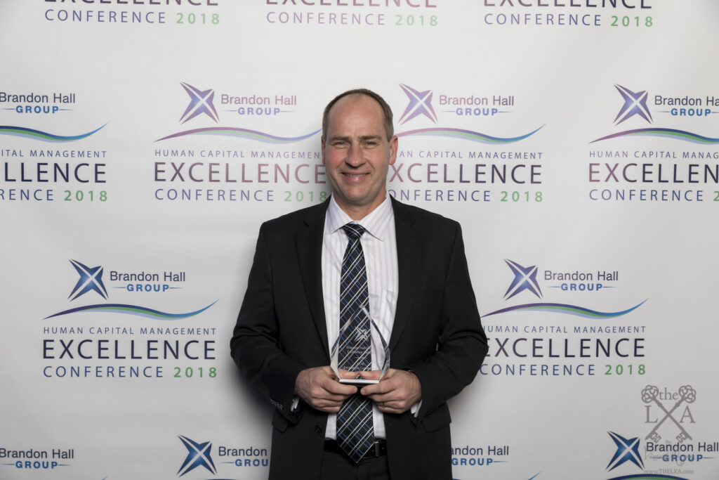 TiER1's CEO Greg Harmeyer accepts the Brandon Hall Group Excellence in Technology Award