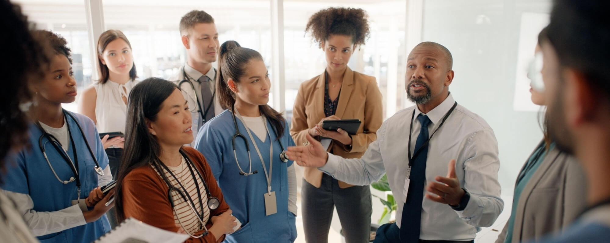 Business team in discussion, diverse group with blue and white attire in office setting.