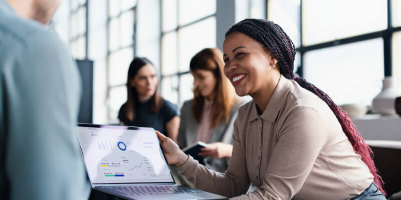 Team of professionals in a meeting, sharing a presentation on a laptop while discussing strategies.