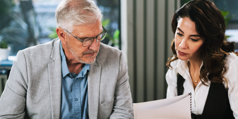 Collaboration, client and people with documents, office and lawyer with engagement letter for case. Law firm, attorney and review of contract with mature man, reading and woman with information