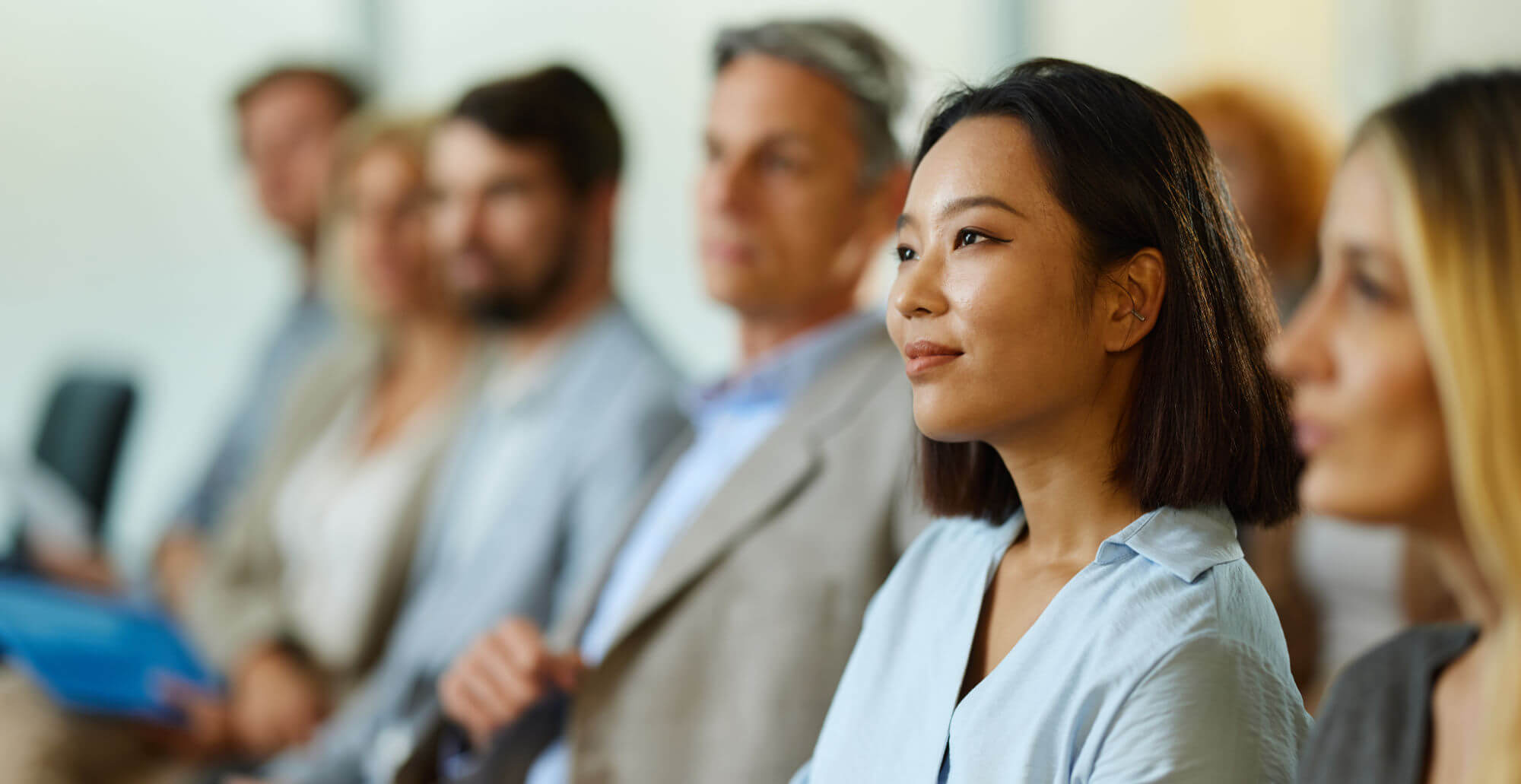 Young smiling Chinese businesswoman and her colleagues attending an education event in the office.