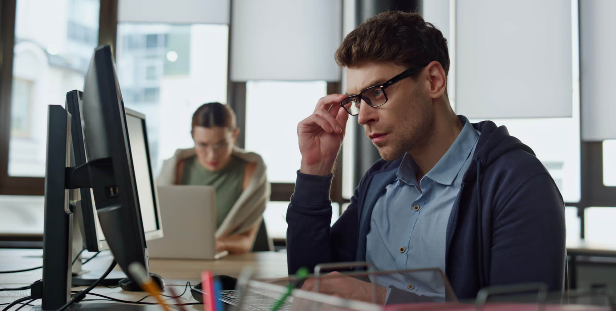 Man concentrating at his computer while a colleague works in the background.