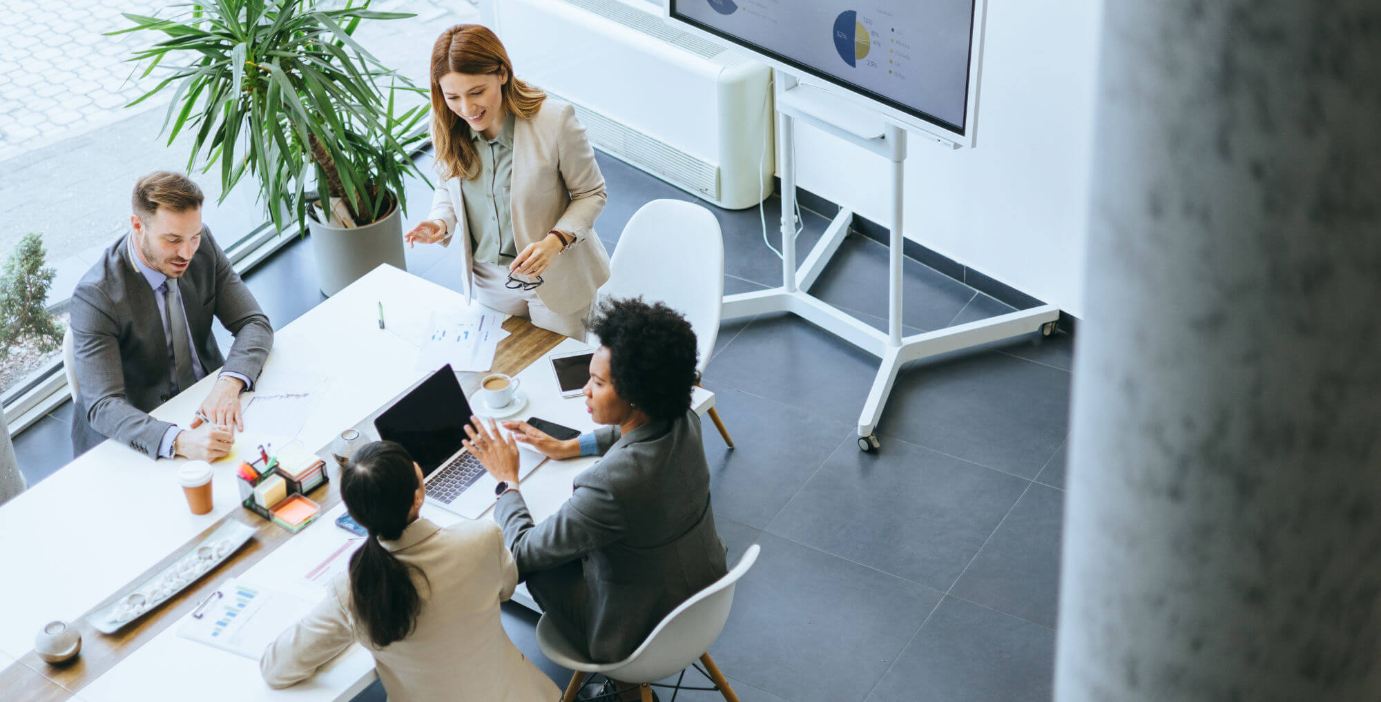 An overhead perspective captures a diverse business team discussing analytics and strategy in a contemporary office meeting