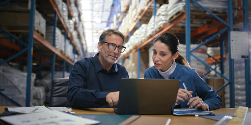 Logistics, laptop and people in warehouse for teamwork, shipping distribution or organizing cargo. Manger, procurement task or factory workers checking for delivery order, stock or ecommerce parcel