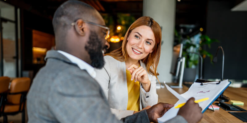 Two colleagues reviewing a document together at a desk.