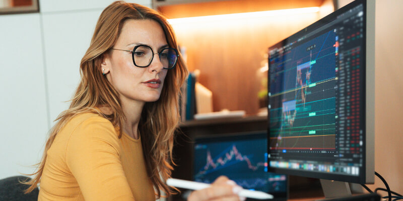 A young woman is sitting in her home and attentively observing the stock market using cryptocurrency graphics