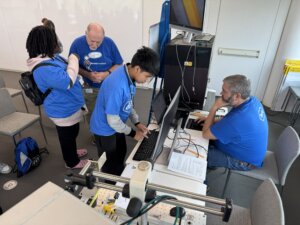 Two students and two Roche volunteers work together at the Engineering station at the 2024 October Career Quest event.