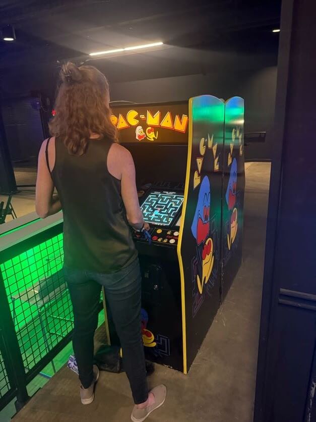 A woman playing Pac-Man on an arcade game.