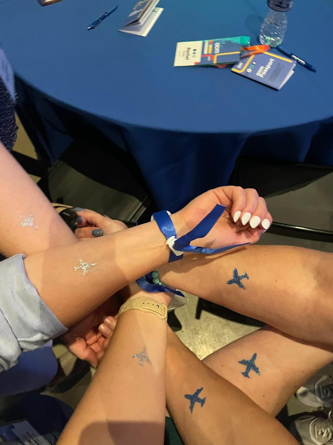 People's arms with a glittery airplane temporary tattoo