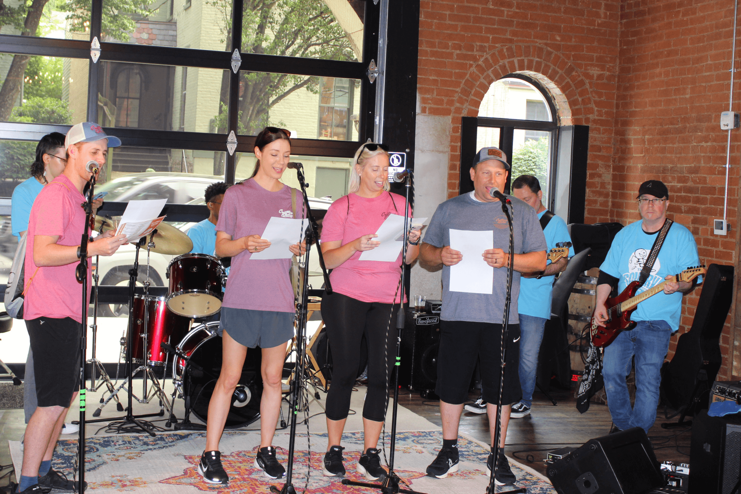 Group of people singing Karaoke while a live band plays behind them.