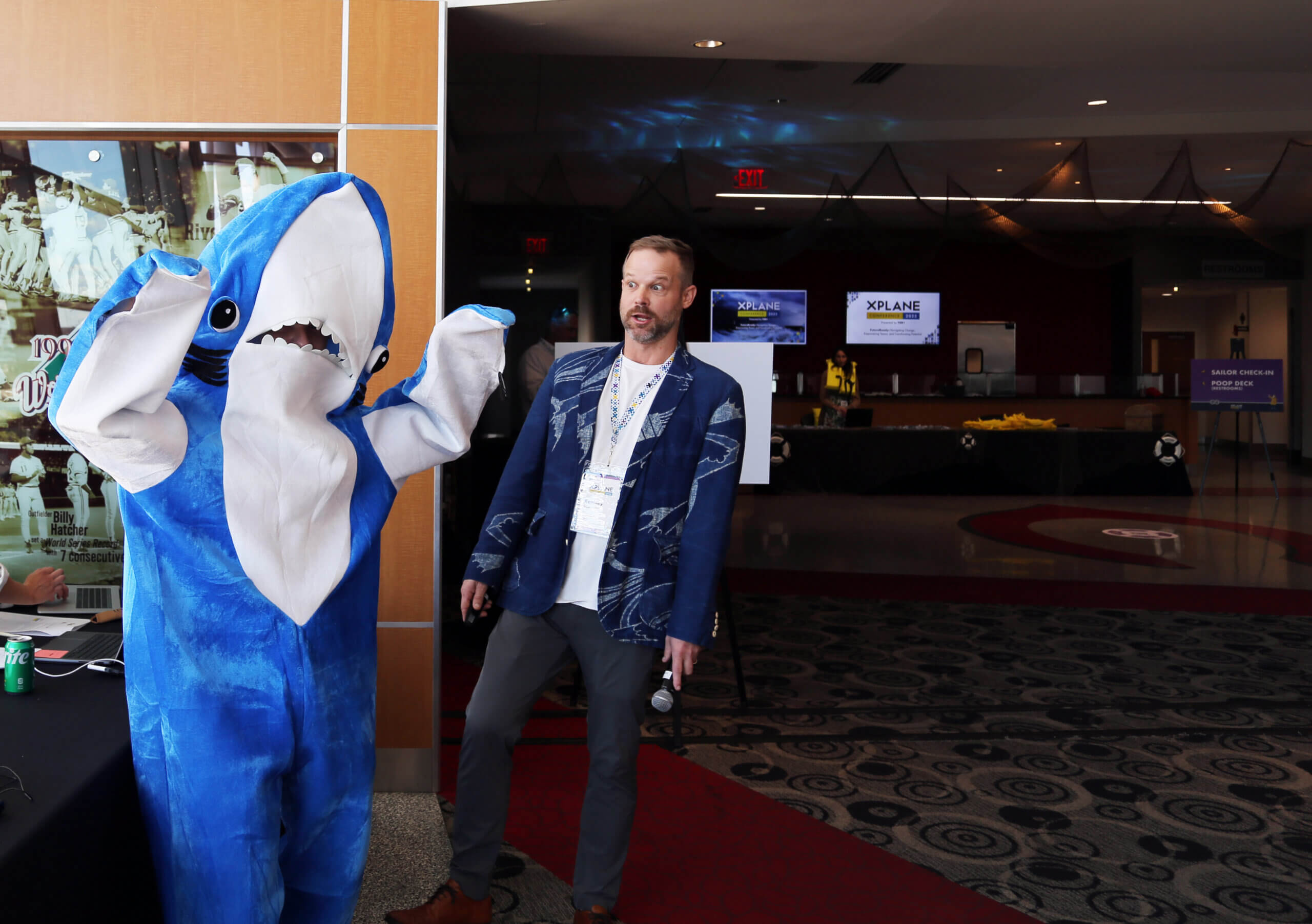 A person is in a shark costume while a man fakes shock and fear.