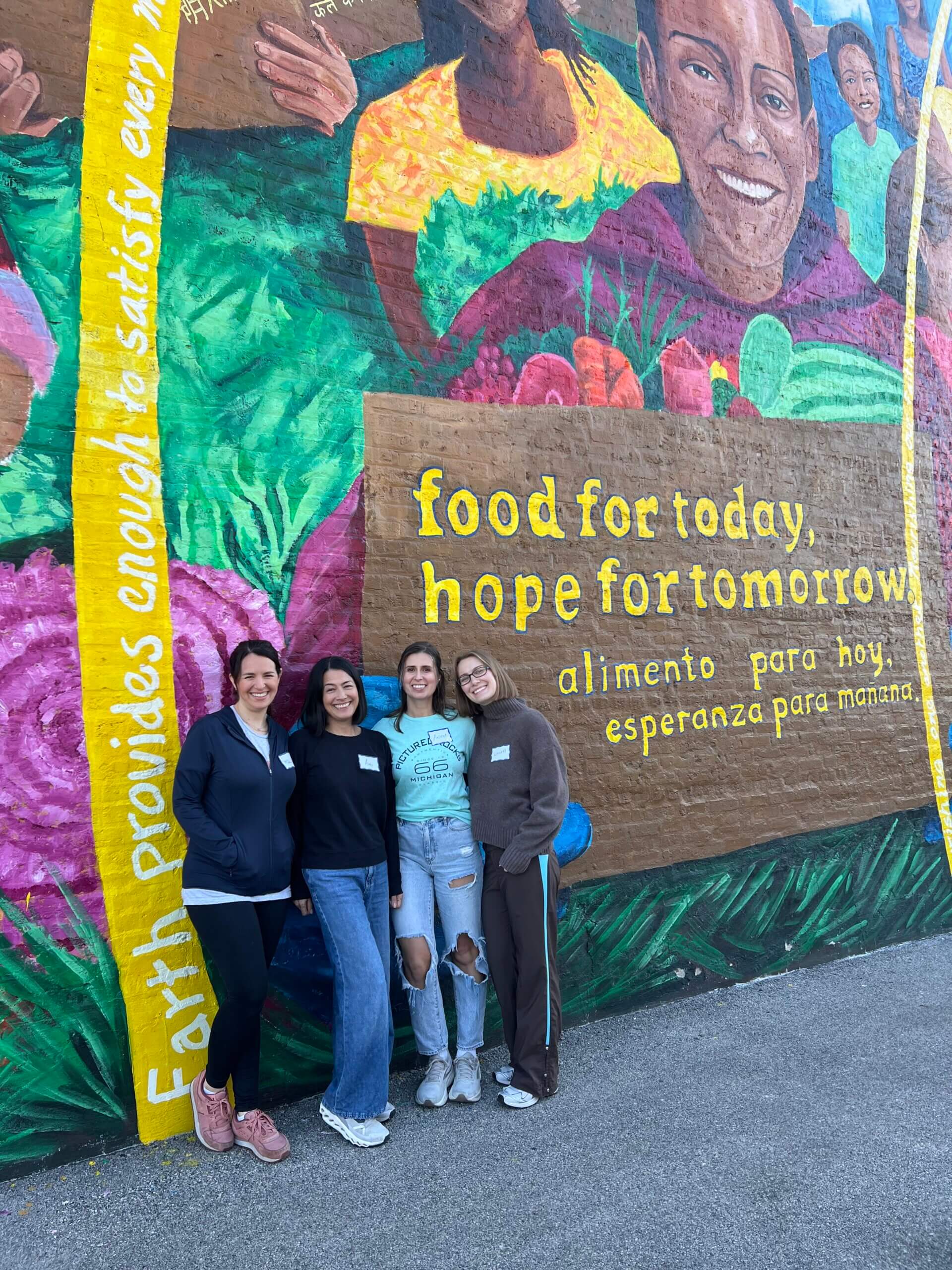 A group of women standing in front of a mural that says food for today, hope for tomorrow.