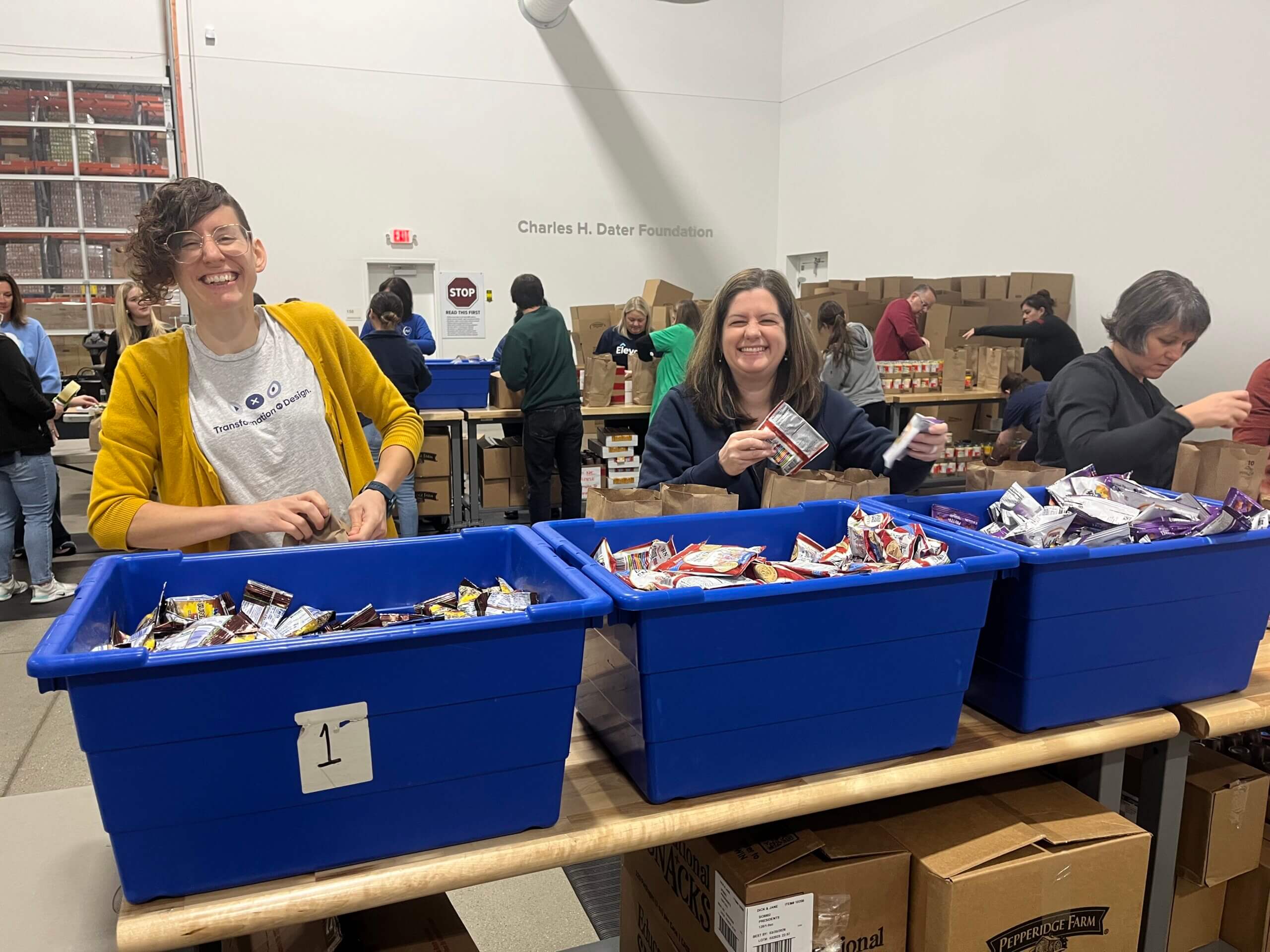 An assembly of people are stuffing power packs of food to go to schools for kids.