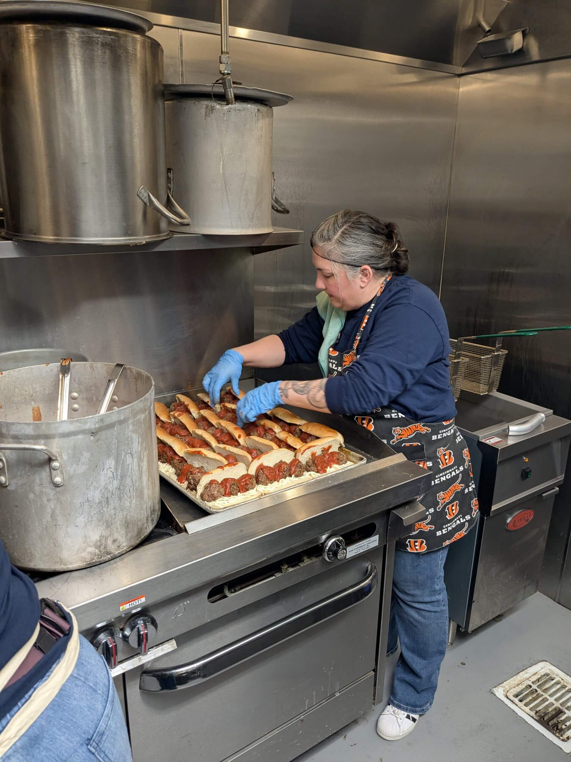 Woman making meatball hoagies in an industrial kitchen.