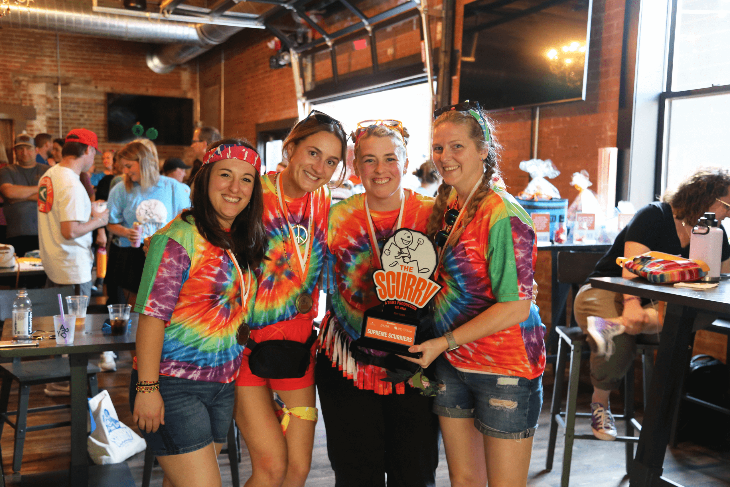 Four women wearing medals and holding a trophy.