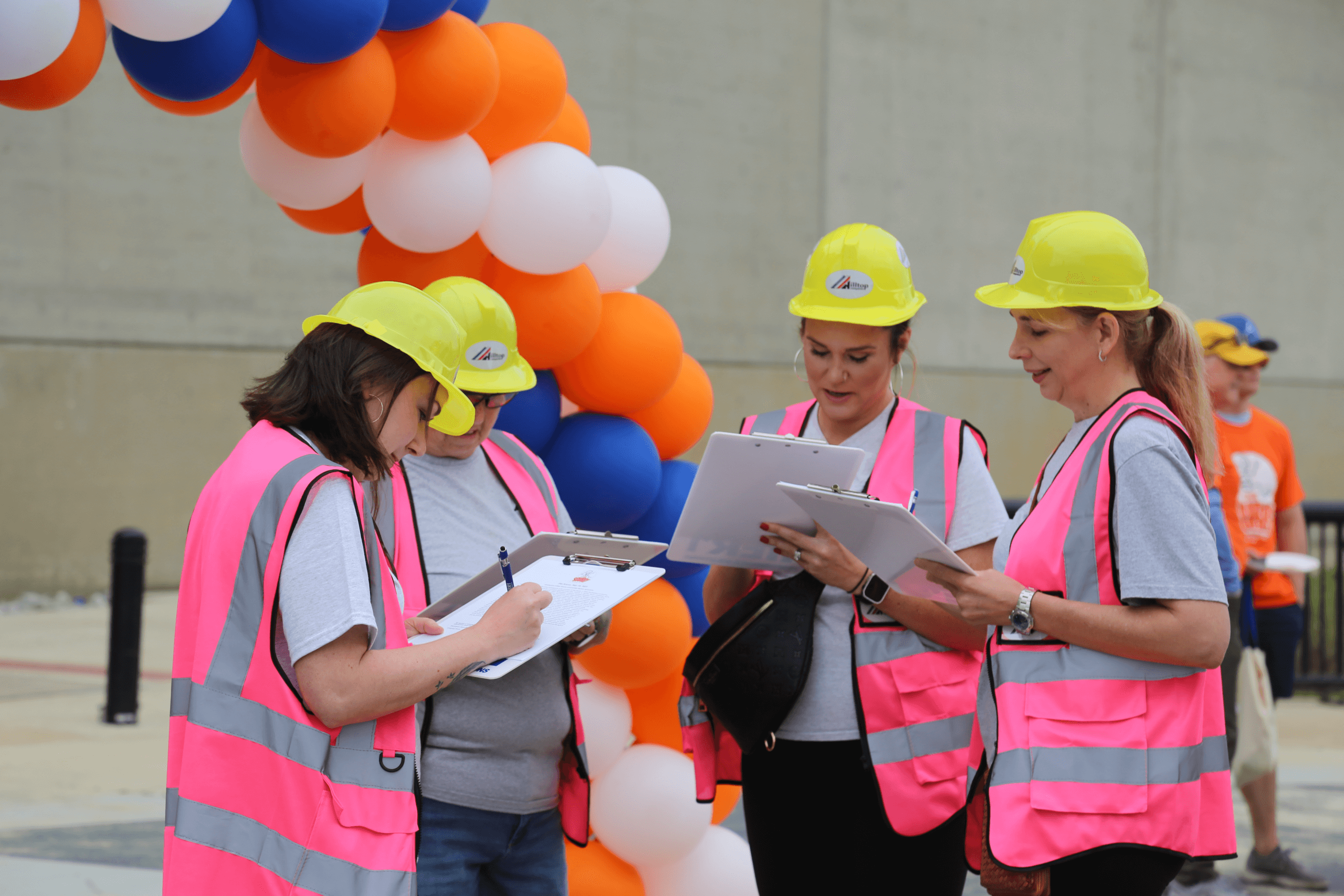 Women wearing construction hates and vests signing waivers.