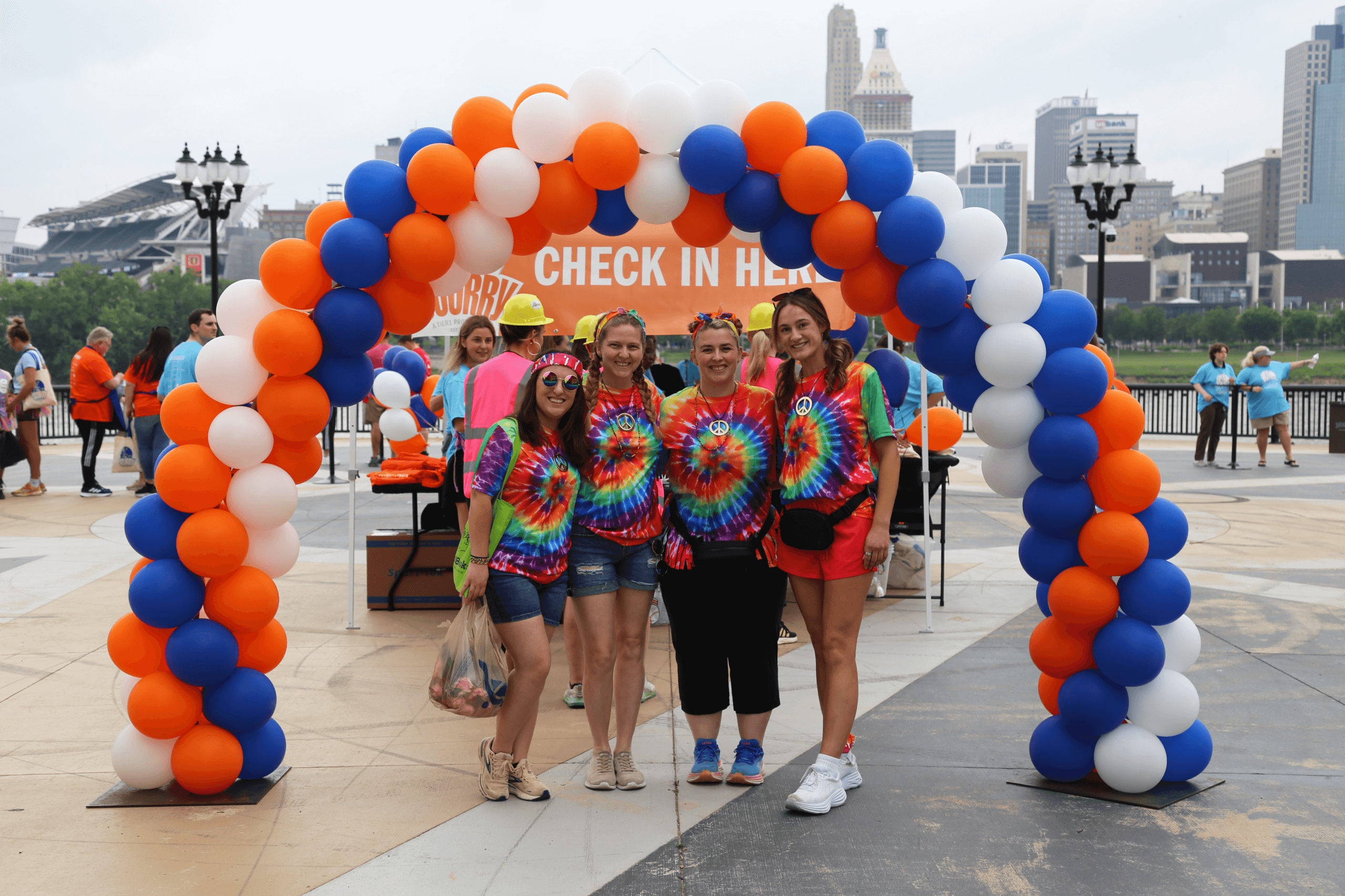 Women in matching tie-dye shirts standing in front of a balloon arch at the Scurry.