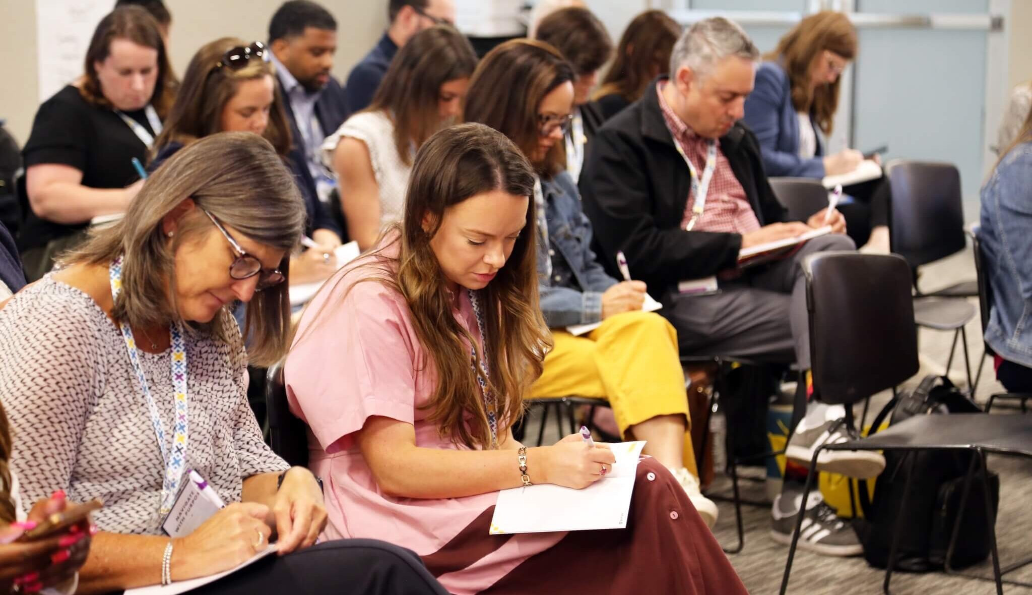 Women writing in notebooks taking notes during a conference.