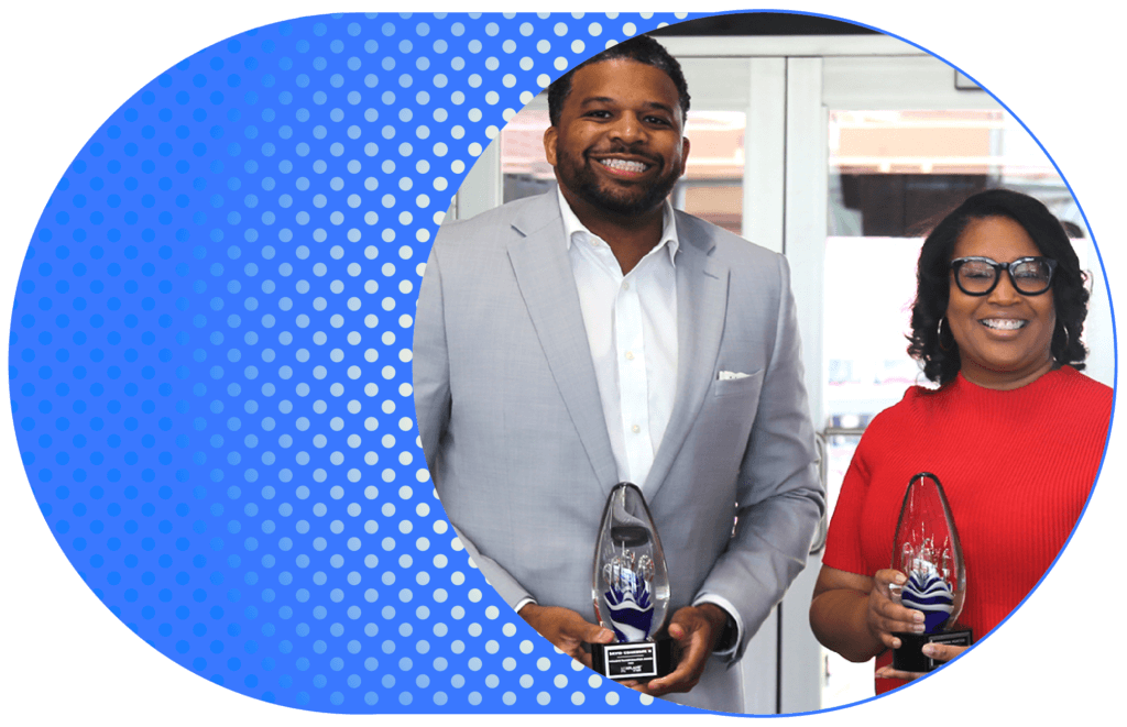 Two smiling award recipients stand side by side holding glass trophies.